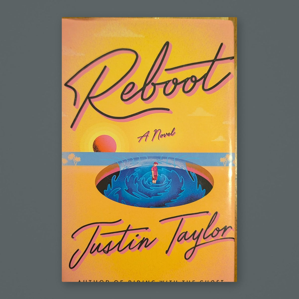 Reboot by Justin Taylor — original physical book on gray slate background