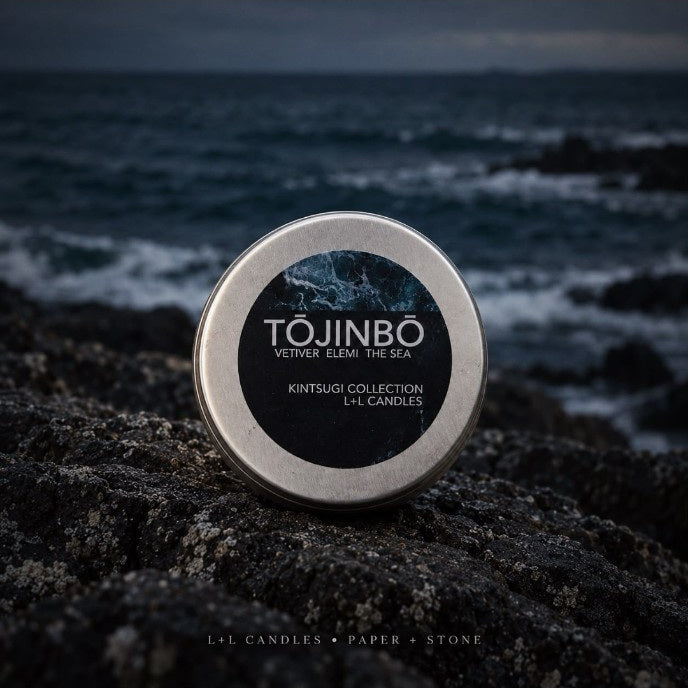 Tōjinbō L+L candle silver lid with vetiver elemi and sea fragrance label photographed against dark ocean waves